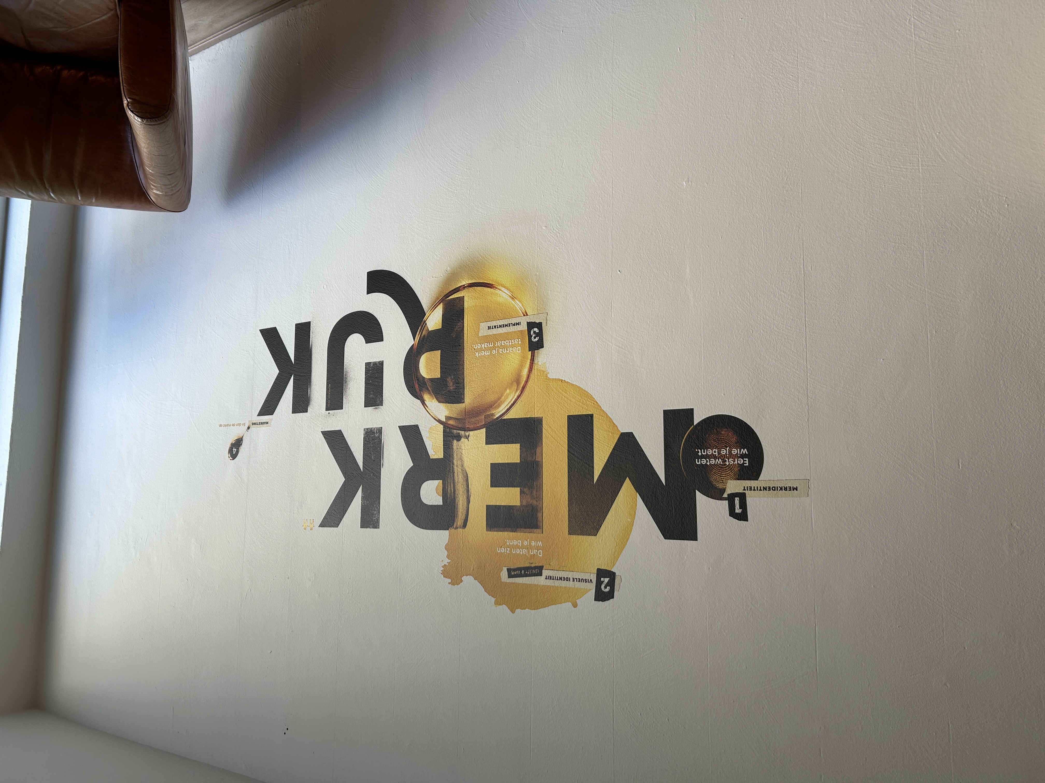 Zakelijke muurprint in de studio van Merkrijk Tilburg, direct op de wand geprint met sterke kleuren, details en strakke vormen.